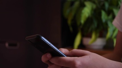 close up of young girl's hands using a smartphone with a plant in the background