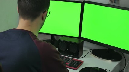 Programmer from behind and programming code on computer monitors.