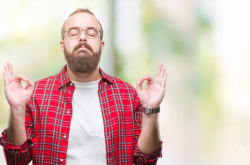 Sticker - Young caucasian hipster man wearing glasses over isolated background relax and smiling with eyes closed doing meditation gesture with fingers. Yoga concept.