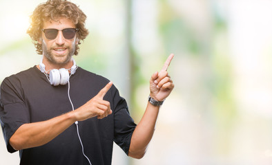 Sticker - Handsome hispanic man listening to music wearing headphones over isolated background smiling and looking at the camera pointing with two hands and fingers to the side.