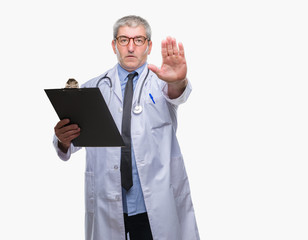 Canvas Print - Handsome senior doctor man holding clipboard over isolated background with open hand doing stop sign with serious and confident expression, defense gesture