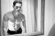 © Tony Marturano - Handsome shirtless man with muscular body and sixpack abs looking at his reflection in bathroom mirror