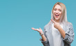 © Krakenimages.com - Young blonde business woman wearing jacket over isolated background amazed and smiling to the camera while presenting with hand and pointing with finger.