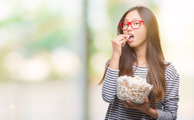 Sticker - Young asian woman eating popcorn over isolated background with a confident expression on smart face thinking serious