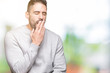 © Krakenimages.com - Young handsome man wearing sweatshirt over isolated background bored yawning tired covering mouth with hand. Restless and sleepiness.
