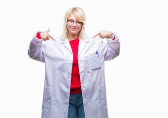 Poster - Young beautiful blonde professional woman wearing white coat over isolated background looking confident with smile on face, pointing oneself with fingers proud and happy.