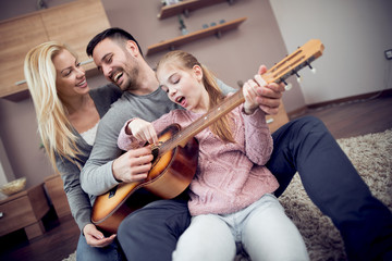 Wall Mural - Smiling family playing guitar in living room