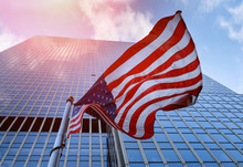 American Flag Waving Against Skyscrapers And A Blue Sky.