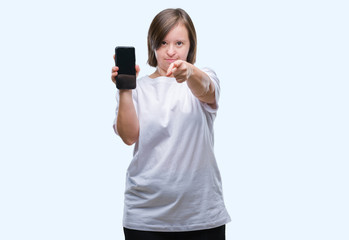 Sticker - Young adult woman with down syndrome showing smartphone screen over isolated background pointing with finger to the camera and to you, hand sign, positive and confident gesture from the front