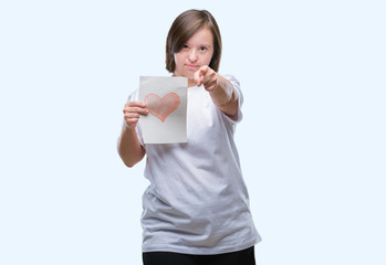 Sticker - Young adult woman with down syndrome holding red heart card over isolated background pointing with finger to the camera and to you, hand sign, positive and confident gesture from the front