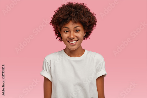 Fotografía Indoor shot of attractive young African American woman with toothy tender smile,