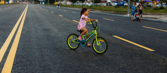 Children learning to drive a bicycle on a driveway outside. Little girls riding bikes on asphalt road in the city wearing helmets as protective gear.