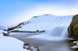 Winter waterfall with hills covered in snow, Iceland