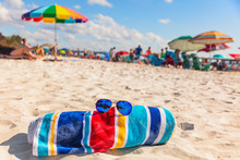 Beach Towel And Fashion Sunglasses On Florida Beach Background -summer Vacation Travel Concept Copy Space. Crowded Popular USA Destination For American Holidays.
