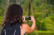 © TheVisualsYouNeed - young happy backpacker woman enjoying holidays trip taking picture with mobile phone of tropical jungle and rice terrace view carrying backpack in tourist travel