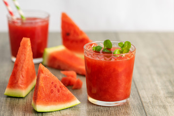 Wall Mural - Glass of Watermelon smoothie with fresh watermelon slices on gray wooden background