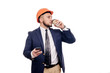 © oes - Business portrait of surprised contractor and developer, talking about phone. Businessman in hard hat with cup of coffee standing over white background. News and coffee brake concept