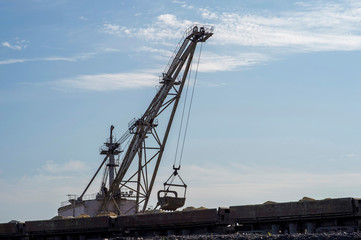 Wall Mural - A huge excavator overloads in the dumps rock from the unloaded train from the mine against a clear blue sky. Concept: mining and environmental problems