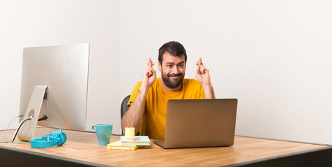 Wall Mural - Man working with laptot in a office with fingers crossing and wishing the best