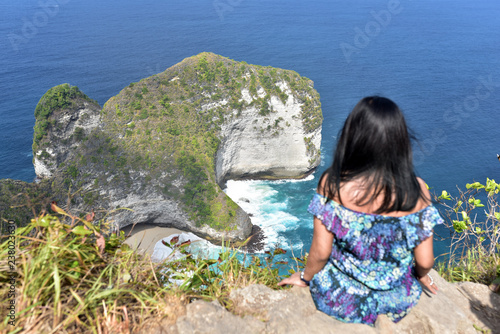 Fotografia Tourist girl enjoying the beautiful landscape of Manta Bay or Kelingking Beach o