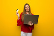 © luismolinero - Young girl with red dress over yellow wall with laptop and credit card