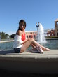mulher sentada na fonte agua e estilosa de pernas de fora