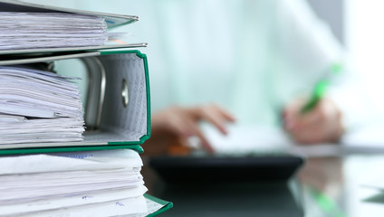 Bookkeeper or financial inspector  making report, calculating or checking balance. Audit and tax service concept. Green colored image background 