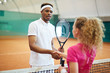 © pressmaster - Young African-american man in activewear shaking hand of his playmate over net on the court