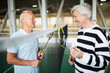 © pressmaster - Two friendly senior badminton players in activewear with rackets standing by net and interacting