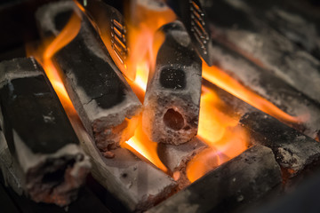 Glowing charcoal embers with BBQ tongs