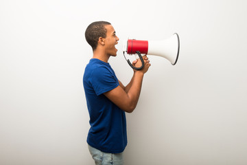 young african american man on white wall shouting through a megaphone to announce something in later