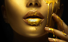 Golden Paint Smudges Drips From The Face Lips And Hand, Golden Liquid Drops On Beautiful Model Girl's Mouth, Creative Abstract Makeup. Beauty Woman Face