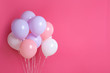 Colorful party balloons on pink background. Space for text