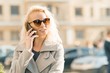 © Valerii Honcharuk - Outdoor portrait of young blonde woman with curly hair smiling and talking on a mobile phone on sunny autumn day in the city