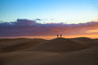 Silhouette of two men taking picture of dusk scenery at famous dunes in Maspalomas, Gran Canaria, Spain