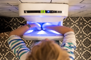 Child using a high-powered hand dryer in a public restroom.