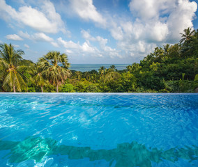 Wall Mural - nfinity  swimming pool overlooking the tropical jungle and the sea, a bright beautiful background for advertising tourism and holidays in tropical countries