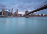 Fototapeta Nowy Jork - View on Brooklyn Bridge and financial district from east river at sunrise with long exposure