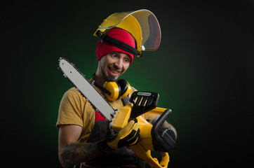 a young man posing on a black background in a work uniform and a construction tool power saw