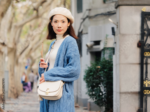 Fotografia Beautiful young brunette woman in blue sweater and white hat looking and smiling