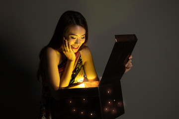 Asian woman opening mystic book box magical light dark background