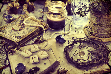 Still life with old tarot cards, runes, roots and black candle on table. Magic gothic ritual. Wicca, esoteric and occult background with vintage objects