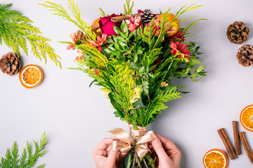 Wall Mural - Women's hands make a winter Christmas bouquet of conifers, roses and chrysanthemums