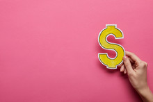 Elevated View Of Hand Holding Yellow Dollar Sign On Pink Background
