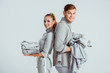 © LIGHTFIELD STUDIOS - smiling couple looking at camera and holding grey clothes isolated on grey