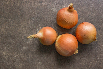 4 onions on a brown stone table, close-up