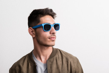 Wall Mural - A confident young hispanic man with sunglasses in a studio.