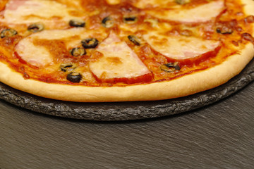 Pizza on a black table. Side view. Homemade tasty little pizza