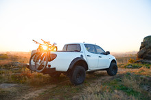 Pickup Offroad Truck With Bikes In The Body In The Mountains At Sunset. Adventure And Car Travel Concept.