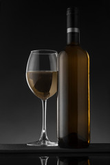 White wine bottle and glass on the black background